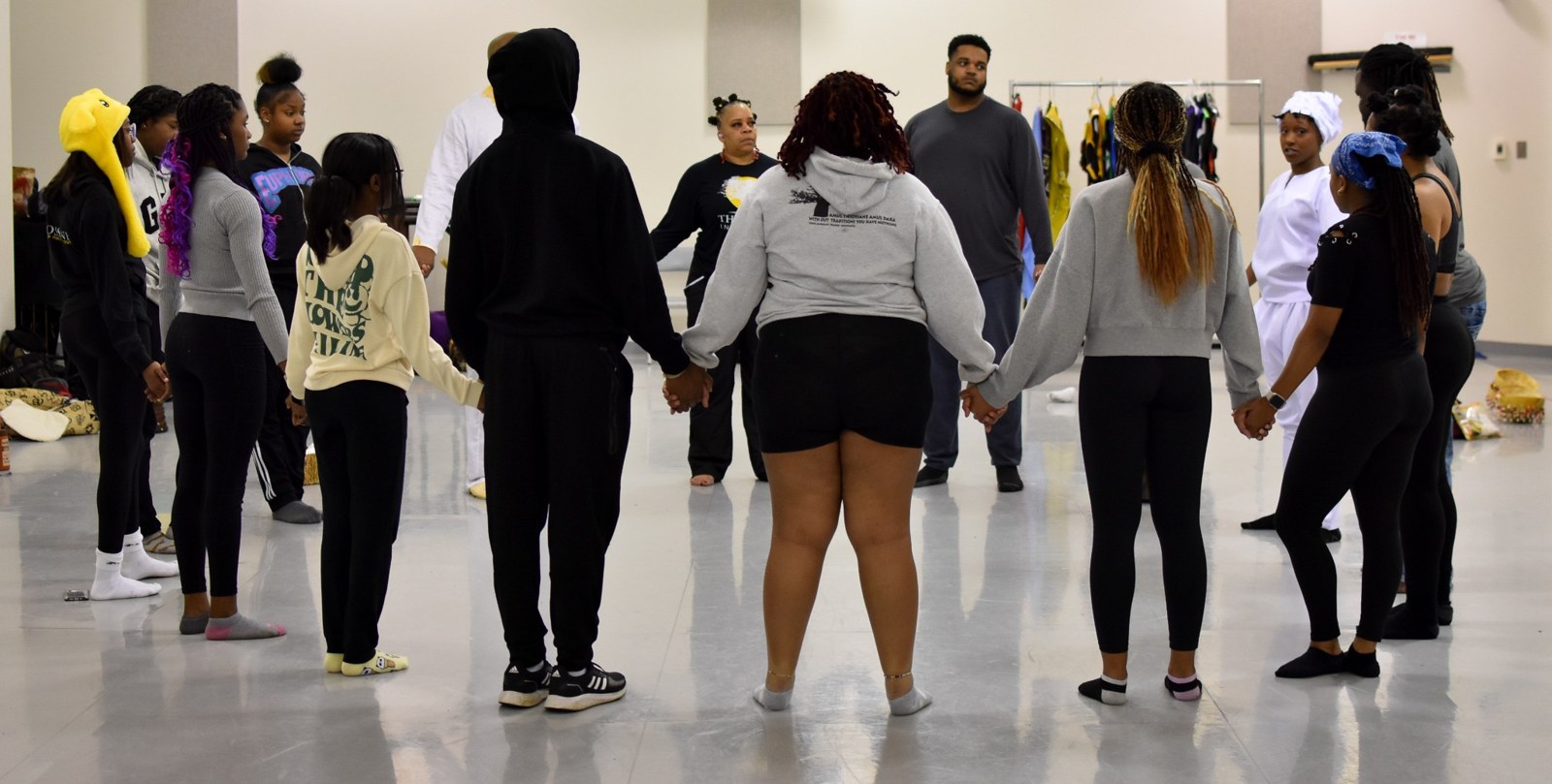 Participants standing together in a circle in a studio
